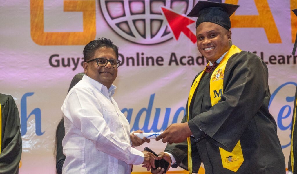 Minister Singh presents a certificate to Michael Younge, who completed his master’s degree through the GOAL programme