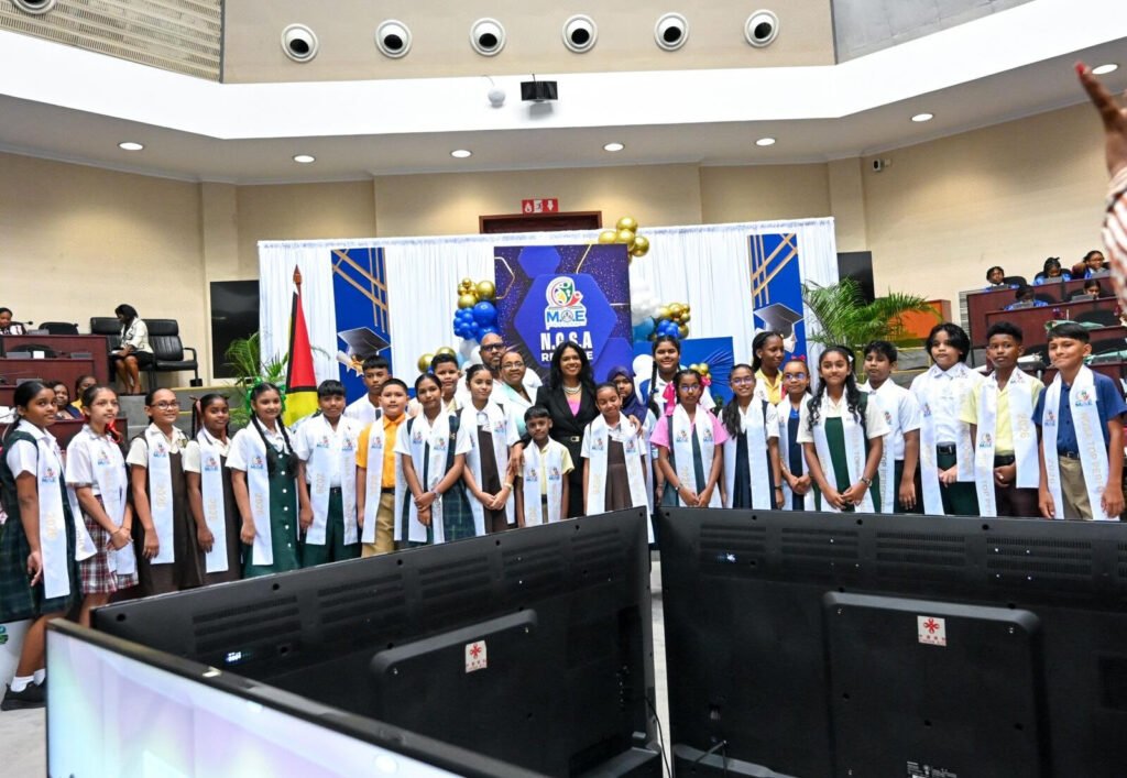 Minister of Education Sonia Parag shares a light moment with the 20 pupils who topped the 2026 NGSA