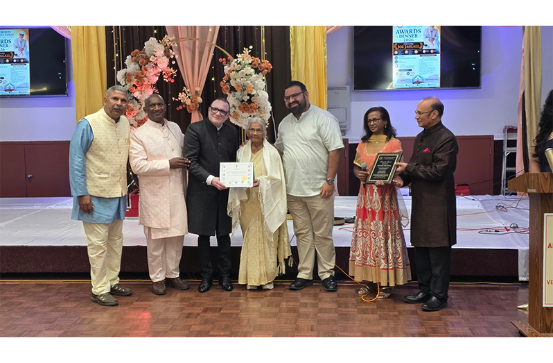 Pandit Virjanand Joe Jaglall receives his award from Arya Samaj representative, accompanied by members of his family.